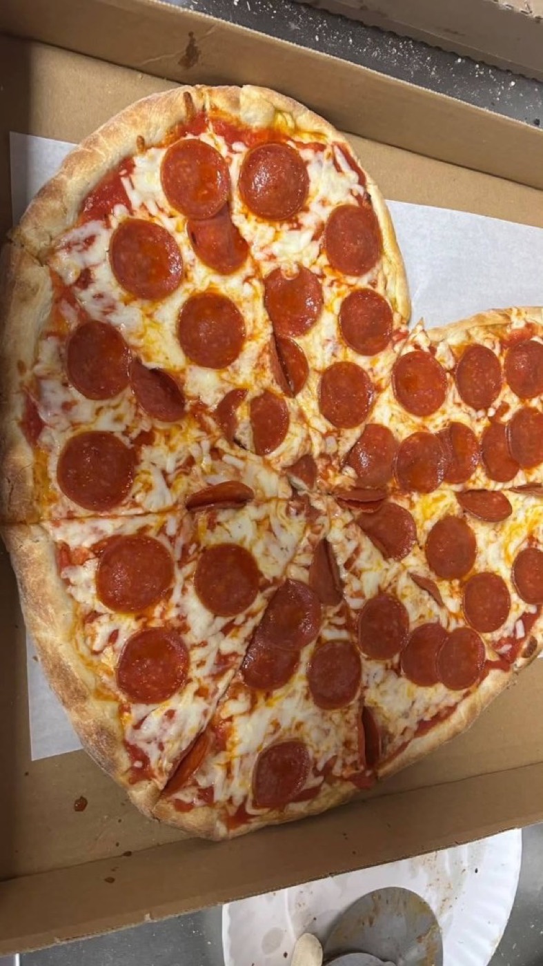Heart-shaped pepperoni pizza in an open cardboard box.
