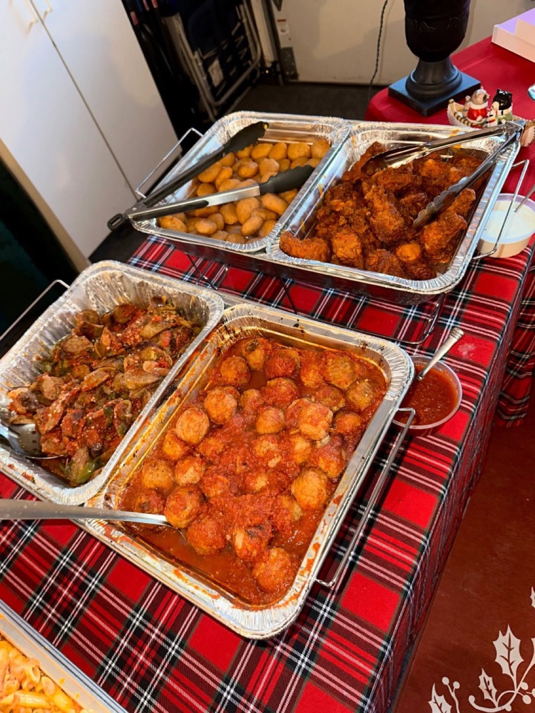 Aluminum catering trays of meatballs, sausage and peppers, and fried appetizers.